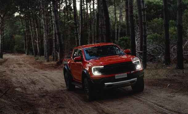 Novo Ranger Raptor laranja andando em estrada de terra a noite